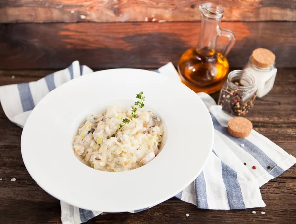 Risotto with mushrooms and chicken on a white plate on a wooden — Stock Photo, Image