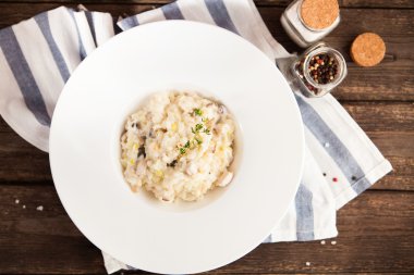 Risotto mantar ve bir tahta üzerinde beyaz bir tabakta tavuk 