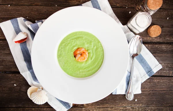 Green Cream of asparagus soup with shrimp in a white bowl on a r — Stock Photo, Image