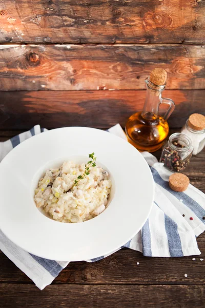 Risotto with mushrooms and chicken on a white plate on a wooden — Stock Photo, Image