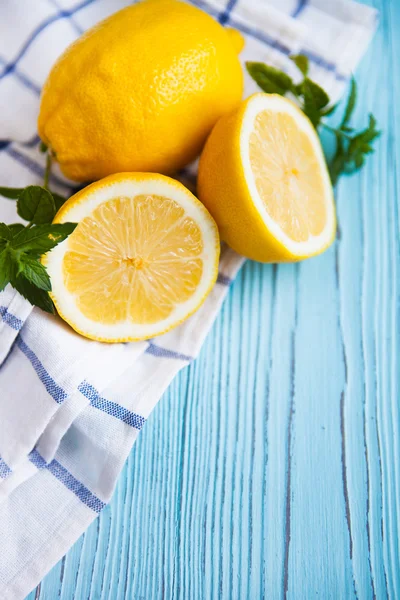 Polovinu čerstvé a celé citrony na modrý venkovský desek. — Stock fotografie