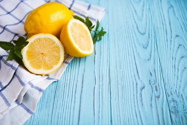 Polovinu čerstvé a celé citrony na modrý venkovský desek. — Stock fotografie