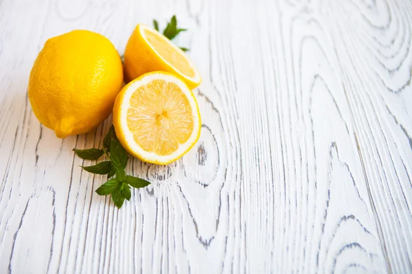 Citrons juteux avec des feuilles de menthe sur un fond en bois blanc. Citron — Photo