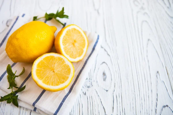 Citrons juteux avec des feuilles de menthe sur un fond en bois blanc. Citron — Photo