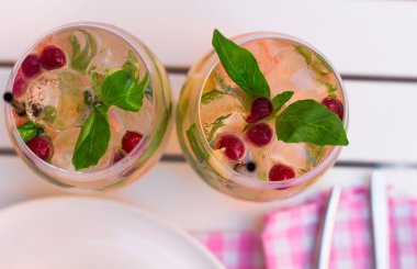 limonade with berries in glassware on wooden table on light blur