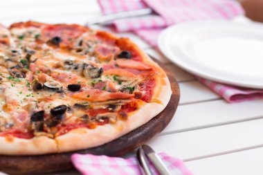 İtalyan lezzetli sıcak pizza beyaz masada ahşap plaka üzerinde