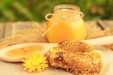 Honey in jar with honeycomb and wooden background.