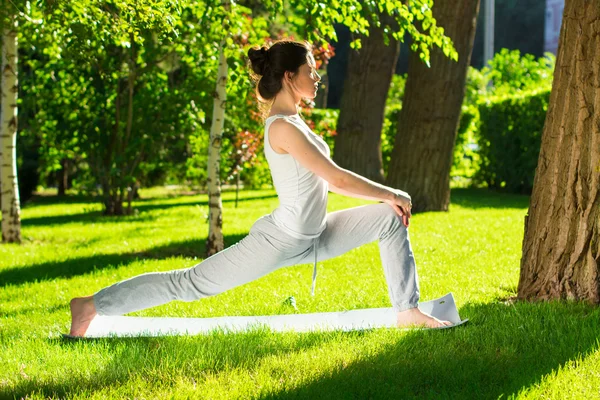 Mujer joven haciendo yoga en el parque por la mañana — Foto de Stock