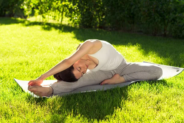 Mujer joven haciendo yoga en el parque por la mañana — Foto de Stock