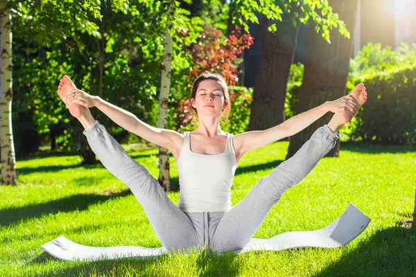 Mujer joven haciendo yoga en el parque por la mañana — Foto de Stock