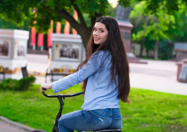 Hermosa mujer con una bicicleta vintage en un parque de la ciudad — Foto de Stock