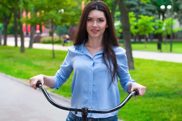 Mulher bonita com uma bicicleta vintage em um parque da cidade — Fotografia de Stock
