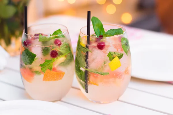 limonade with berries in glassware on wooden table on light blur