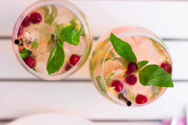 Limonade with berries in glassware on wooden table on light blur — Stockfoto