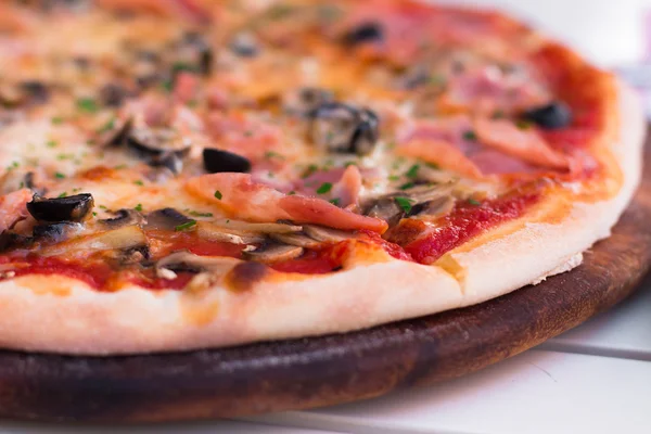 Włoski zachwycający gorąca pizza na drewnianej tablicy, na biały stół — Zdjęcie stockowe