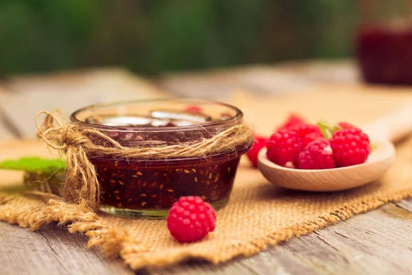Fresh raspberries and jam on wooden table — ストック写真