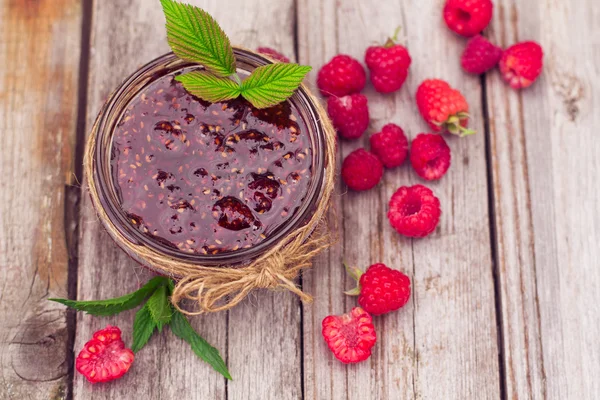 Frambozenjam in een kruik en verse bessen op de houten tafel — Stockfoto