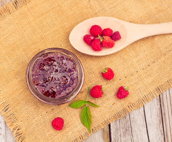 Fresh raspberries and jam on wooden table — Stockfoto