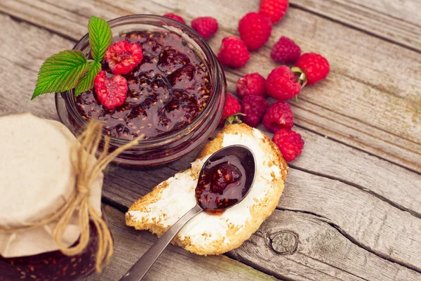 Marmellata di lampone in un vaso e bacche fresche sul tavolo di legno — Foto Stock