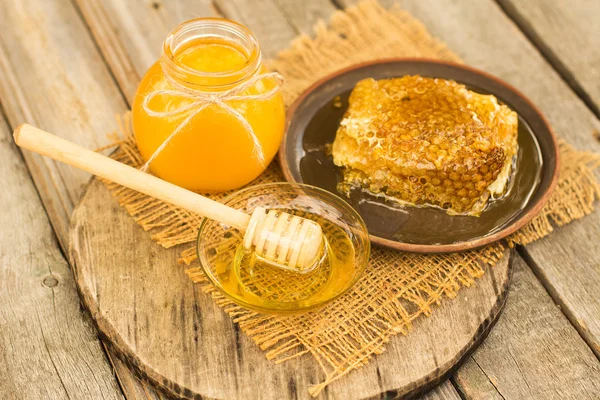 Miel en tarro con panal y fondo de madera . — Foto de Stock