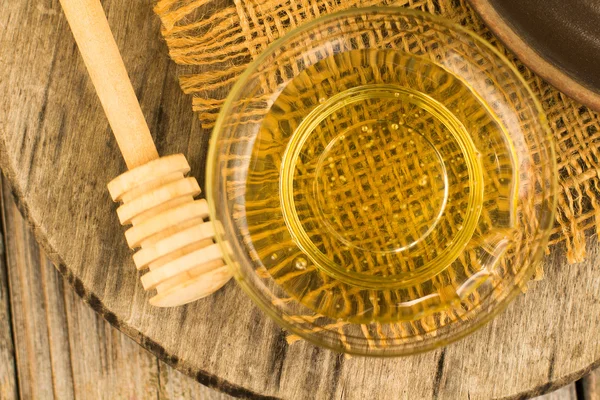 Miel goteando de un tarro de miel de madera sobre un fondo borroso —  Fotos de Stock