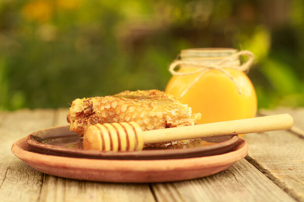 Honey in jar with honeycomb and wooden background.
