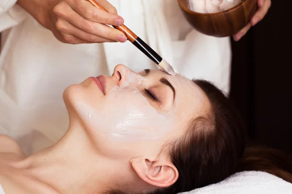 Tratamiento de spa. Hermosa mujer con máscara facial en el salón de belleza . — Foto de Stock