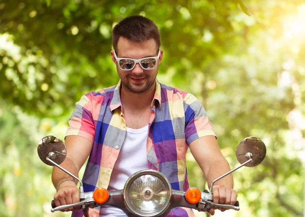 Handsome young man in sunglasses sitting on a scooter — Stockfoto