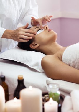 Prettyl woman with facial mask at beauty salon. Spa treatment