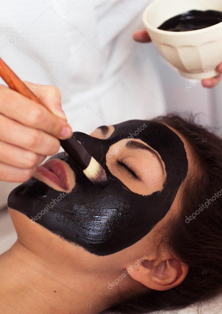 Prettyl woman with facial mask at beauty salon. Spa treatment