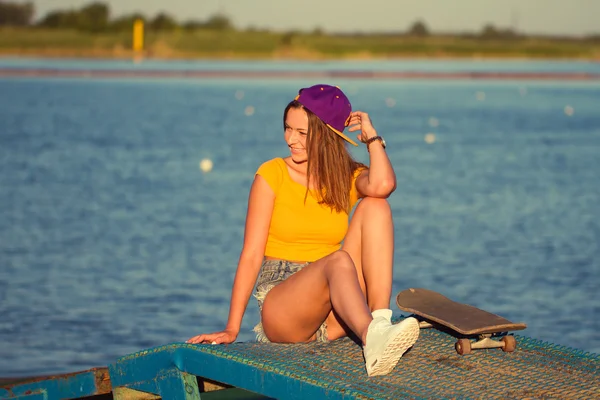 Mujer joven hermosa y de moda posando con un monopatín — Foto de Stock