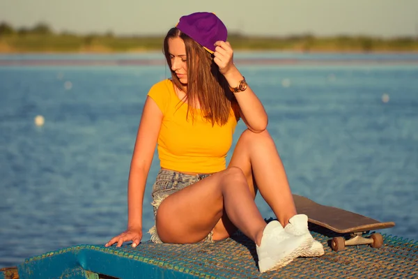 Mujer joven hermosa y de moda posando con un monopatín — Foto de Stock