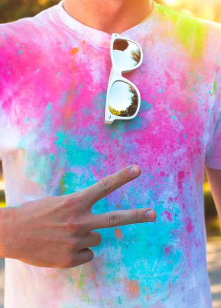 A young man shows the symbol of peace and friendship . Holi fest — ストック写真