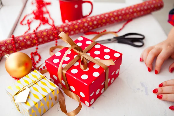 Female hands wrapping xmas gifts into paper and tying them up wi — Stock Photo, Image