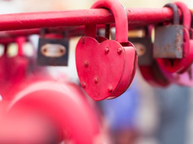 Kırmızı asma kilitler kalp şekilli, bulanık bir arka plan üzerinde yakın çekim. 