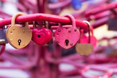 Kırmızı asma kilitler kalp şekilli, bulanık bir arka plan üzerinde yakın çekim.