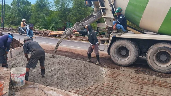 Beton Yol Yapımı: İnşaat Alanında Çelik Takviyesi Üzerine Karışımı Düzleştiren İşçilerle Karışık Kamyon Çimento Dökümü