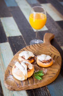 Tarçınlı ev yapımı çörekler ve bir bardak meyve suyu.