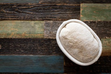 Ahşaptan yapılmış bir masada, bir sepetin içinde ekmek hamuru