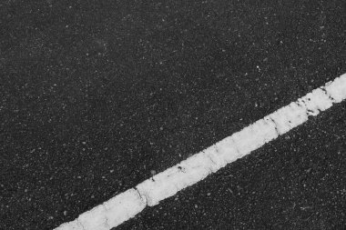 Beyaz yol çizgilerinin olduğu bir parktaki yolun görüntüsü görüntünün altında eğimli bir şekilde kesişiyor. Yol ya da trafik uygulamalarında kullanılabilir