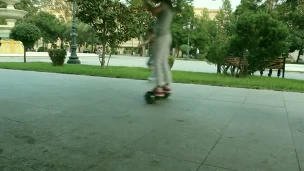 Дети на самобалансирующемся скутере и роликовых коньках в парке — стоковое видео