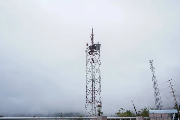 A cellular communications tower, with many antennas, in dense fog