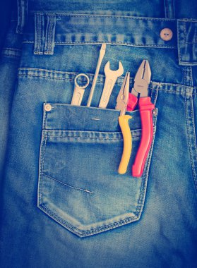 Several tools on a denim workers pocket. clipart