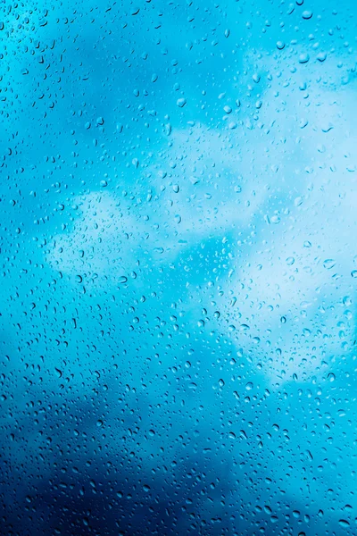 Gotas de agua en un vaso de ventana después de la lluvia. El cielo con nubes en el fondo . — Foto de Stock