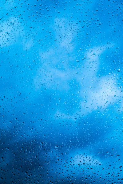 Wasser tropft nach dem Regen auf ein Fensterglas. der Himmel mit Wolken im Hintergrund. — Stockfoto