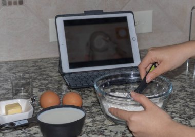 Ev hanımı evde online video izleyerek krep yapmayı öğreniyor.