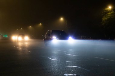 Sisli bir gecede yüksek kirişleri kullanan araçların yol manzarası