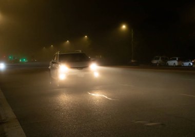 Sisli bir gecede yüksek kirişleri kullanan araçların yol manzarası