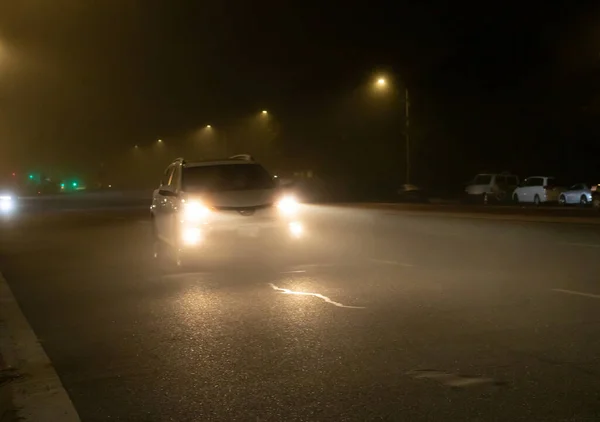Sisli bir gecede yüksek kirişleri kullanan araçların yol manzarası