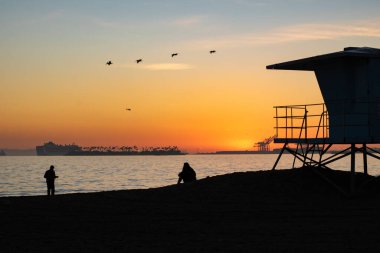 Long Beach yakınlarındaki cankurtaran ve ziyaretçilerin günbatımı manzarası